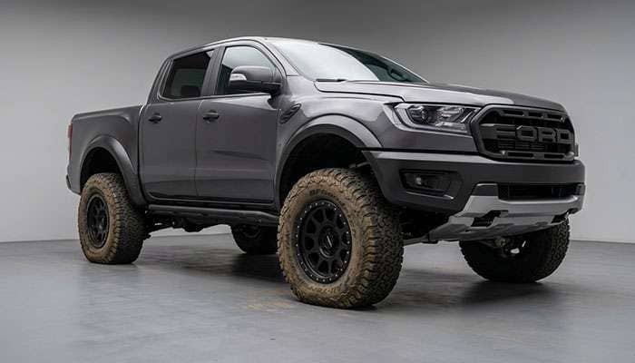 Four-wheel-drive truck driving on soft sand with visibly aired-down tires showing the wider footprint that lets the vehicle float on the surface