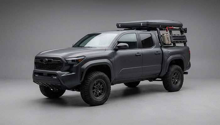 Pickup truck with rugged terrain R/T tires set up for overlanding with rooftop tent and recovery gear on a dirt forest service road