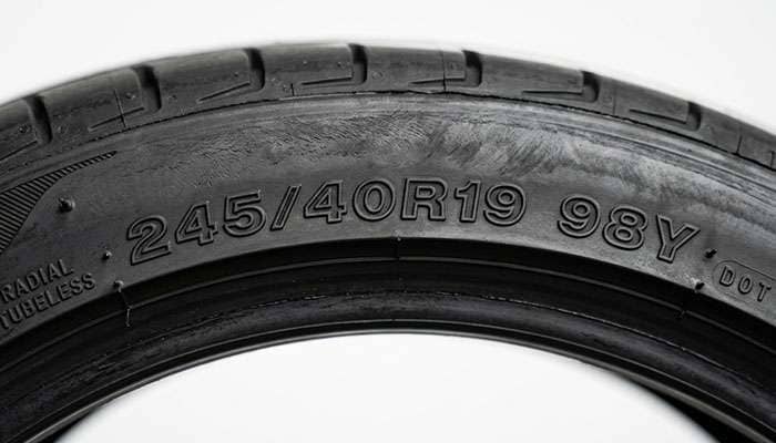 Close-up of a tire sidewall showing the load index and speed rating letter stamped after the tire size