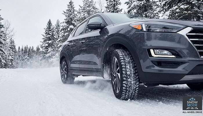 Hyundai Tucson navigating a snowy forest road with winter tires, showcasing traction and safety in cold conditions