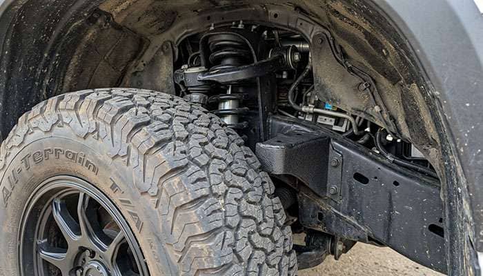Inside the front wheel well of a leveled Toyota Tundra at full steering lock showing the gap between a 35-inch tire and the cab mount