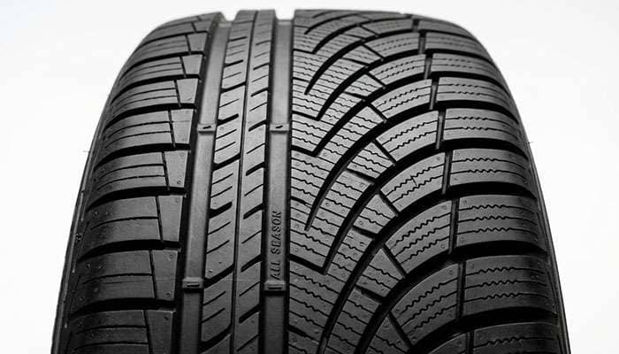 Close-up of an ultra-high-performance all-season tire tread pattern showing asymmetric design with deep siping for wet traction