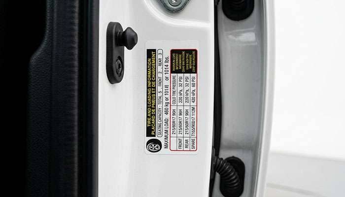 Vehicle door jamb tire placard showing recommended tire size and load information