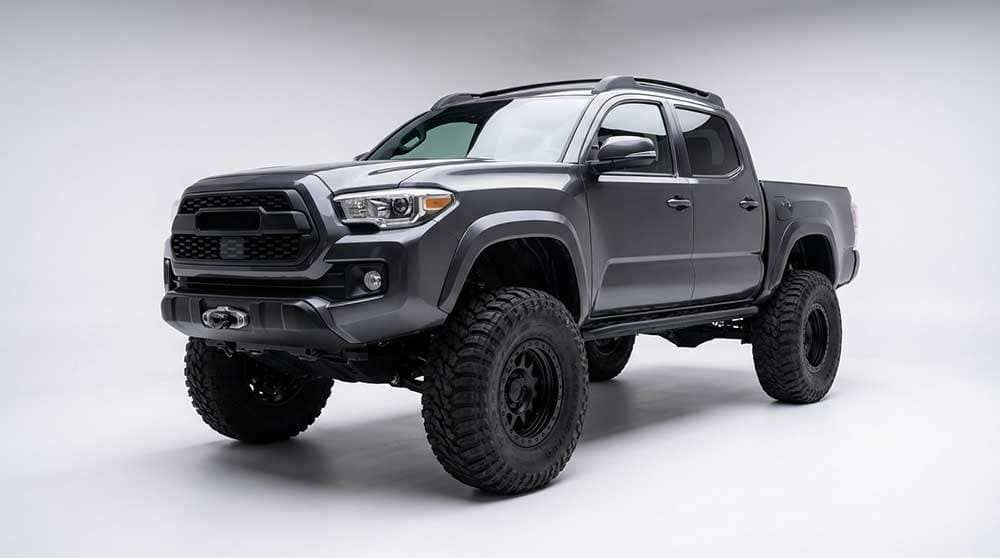 Lifted off-road truck with large aggressive tires mounted on black beadlock wheels in outdoor setting