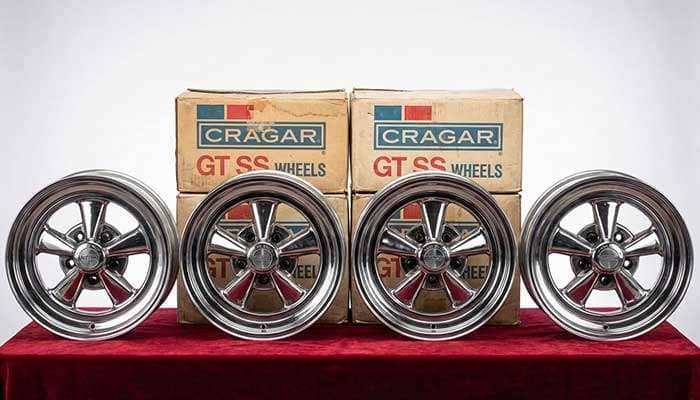 Four vintage Cragar GT SS 15x6 chrome wheels with 5x4 3/4 bolt pattern displayed on a red surface with boxes behind