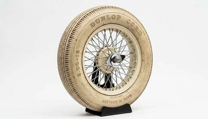 Vintage cream-colored rubber tire mounted on a classic car wheel