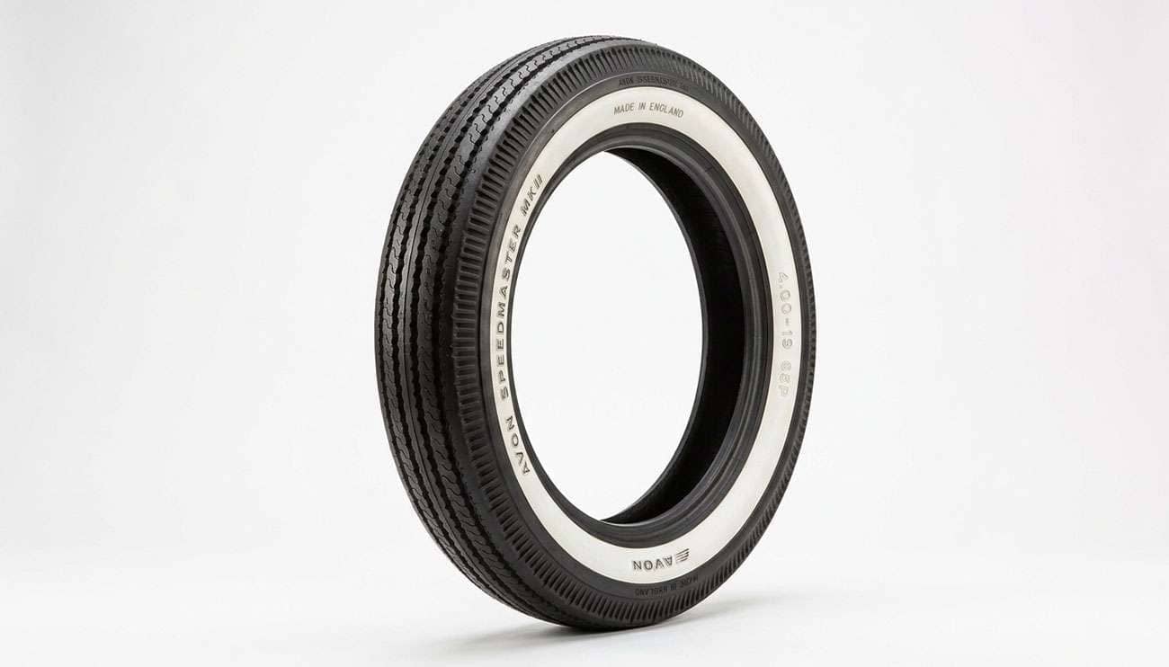 A vintage whitewall motorcycle tire displayed against a clean white studio backdrop