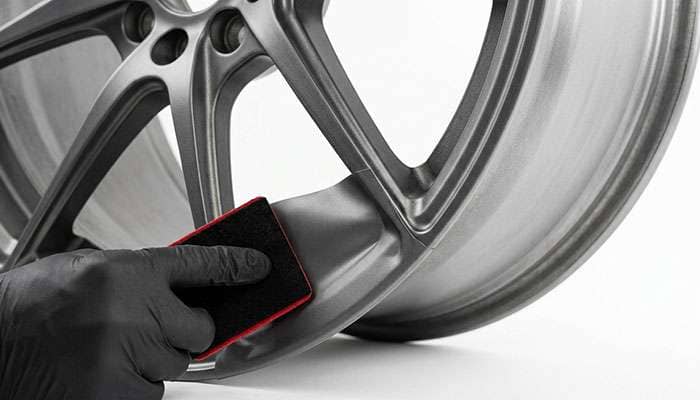 Detail of vinyl wrap film being conformed around the spoke junction of an alloy wheel