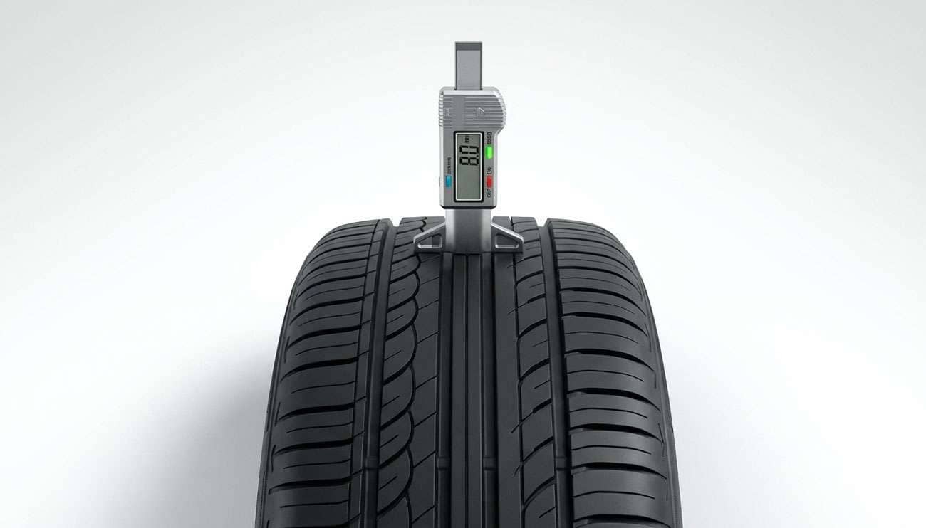 Tire tread depth gauge measuring remaining tread on a new tire