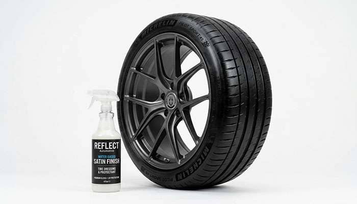 Bottle of water-based tire dressing beside a freshly dressed black tire