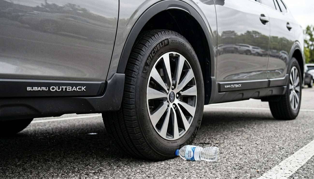 Empty plastic water bottle wedged against a car tire in a parking lot carjacking scam