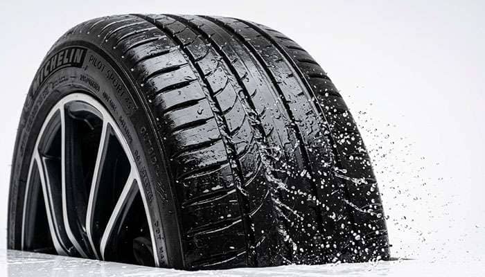 Wet car tire tread with water channeling out through the grooves