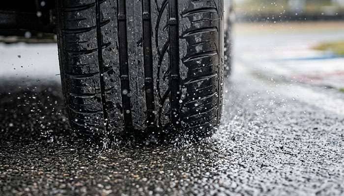 Close-up of high-performance tire making contact with wet asphalt track surface