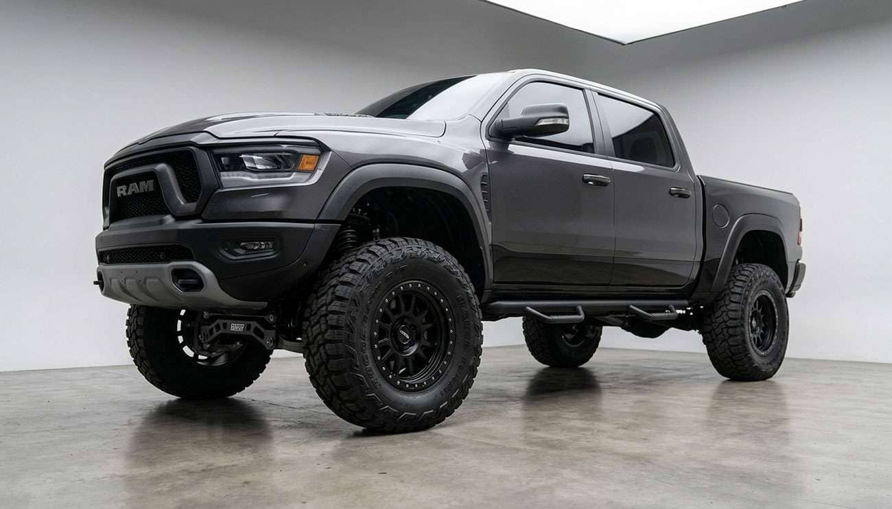 Lifted pickup truck with aggressive rugged terrain R/T tires parked on a dirt trail with mountains in the background