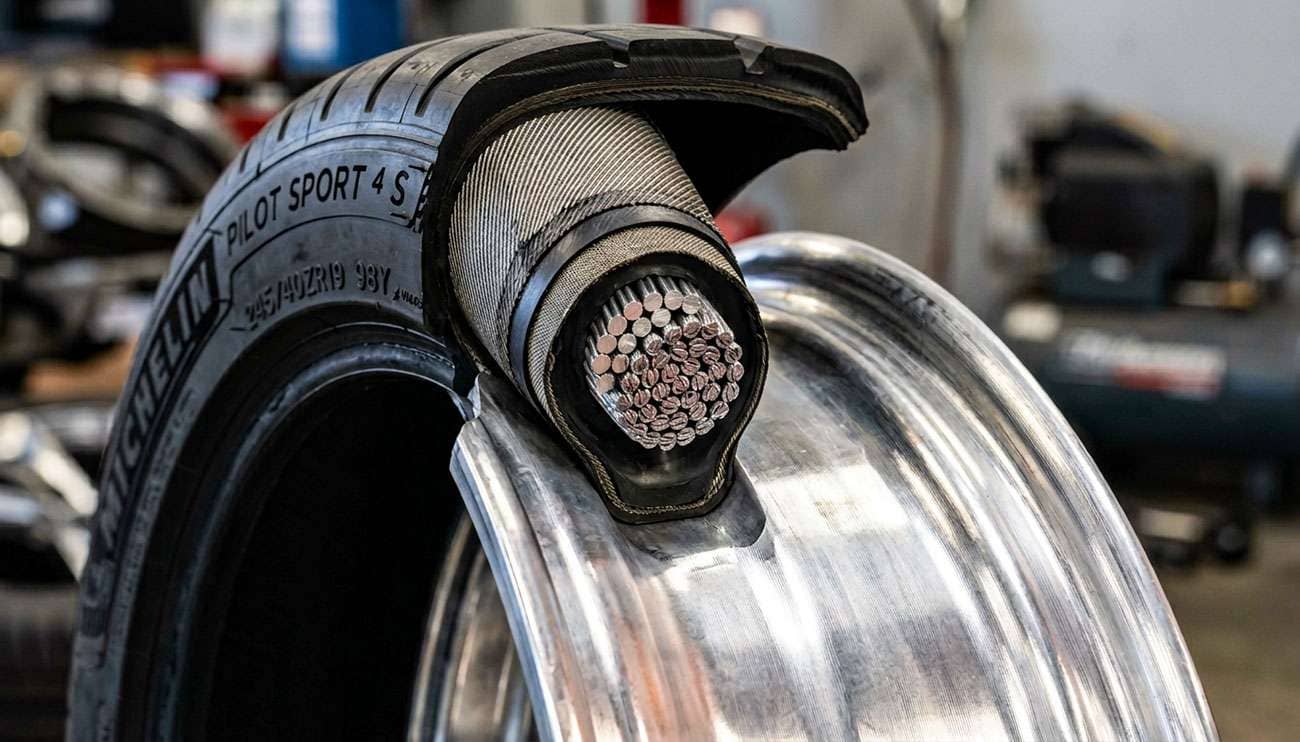 Close-up cross-section diagram of a tire bead seated on a wheel rim showing steel wire bundle and rubber coating