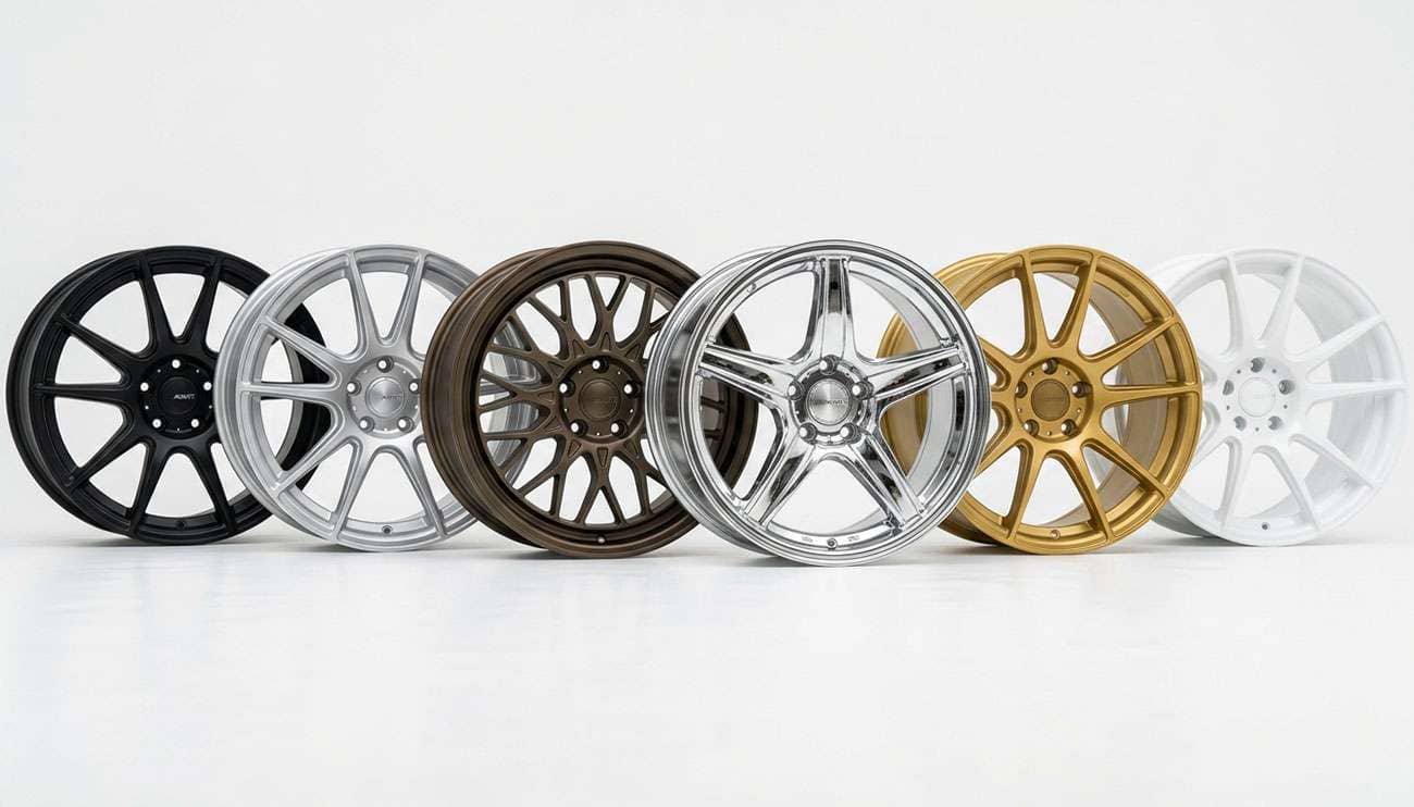 Aftermarket wheels in black, silver, bronze, chrome, gold, and white finishes arranged on a clean white studio backdrop
