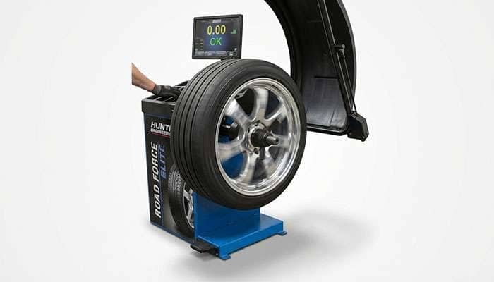 Close-up of a car wheel being balanced on a tire balancing machine in an auto repair shop