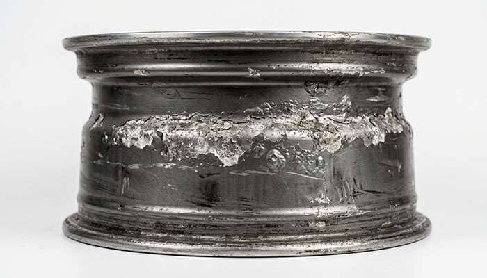 dismounted aluminum wheel showing blistered flaking finish and white oxide buildup along the bead seat sealing surface