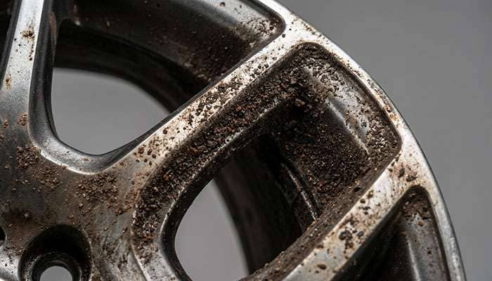 Detail of brake dust accumulation on aftermarket wheel spoke showing the metallic particles that damage wheel finishes
