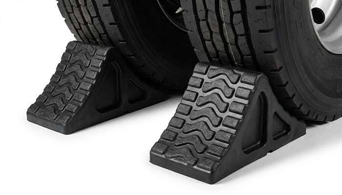 Rubber wheel chocks positioned behind vehicle tires for safety