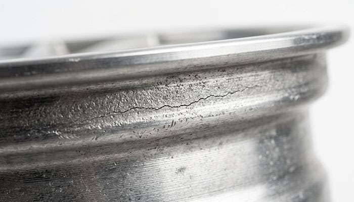 Close-up of a hairline crack running along the inner barrel of an aluminum wheel behind the bead seat