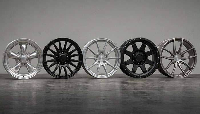 Five different aftermarket wheel designs lined up showing range from classic five-spoke to modern split-spoke styles