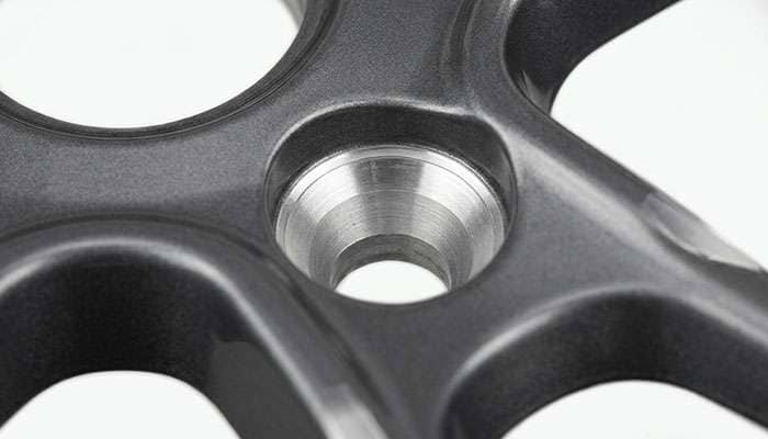 Close-up of a wheel lug hole showing the tapered conical seat shape used to identify the correct lug nut