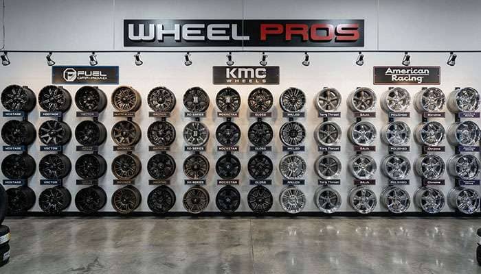Collection of various Wheel Pros brand wheels including Fuel, KMC, American Racing displayed on showroom wall