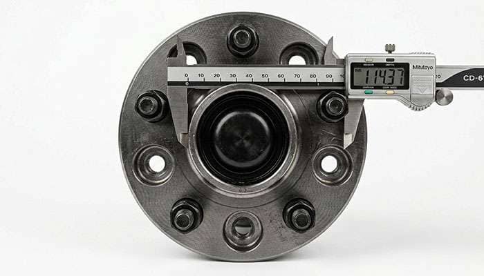 Measuring a wheel bolt pattern with calipers to confirm the correct lug spacing