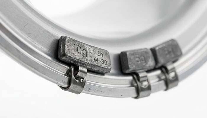 Close-up detail of clip-on wheel weights attached to the inner rim flange of an alloy wheel