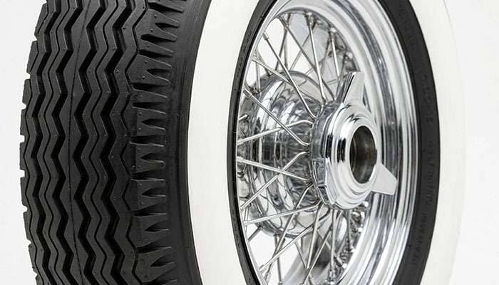 Side-on close-up of wide whitewall tire showing molded whitewall construction detail