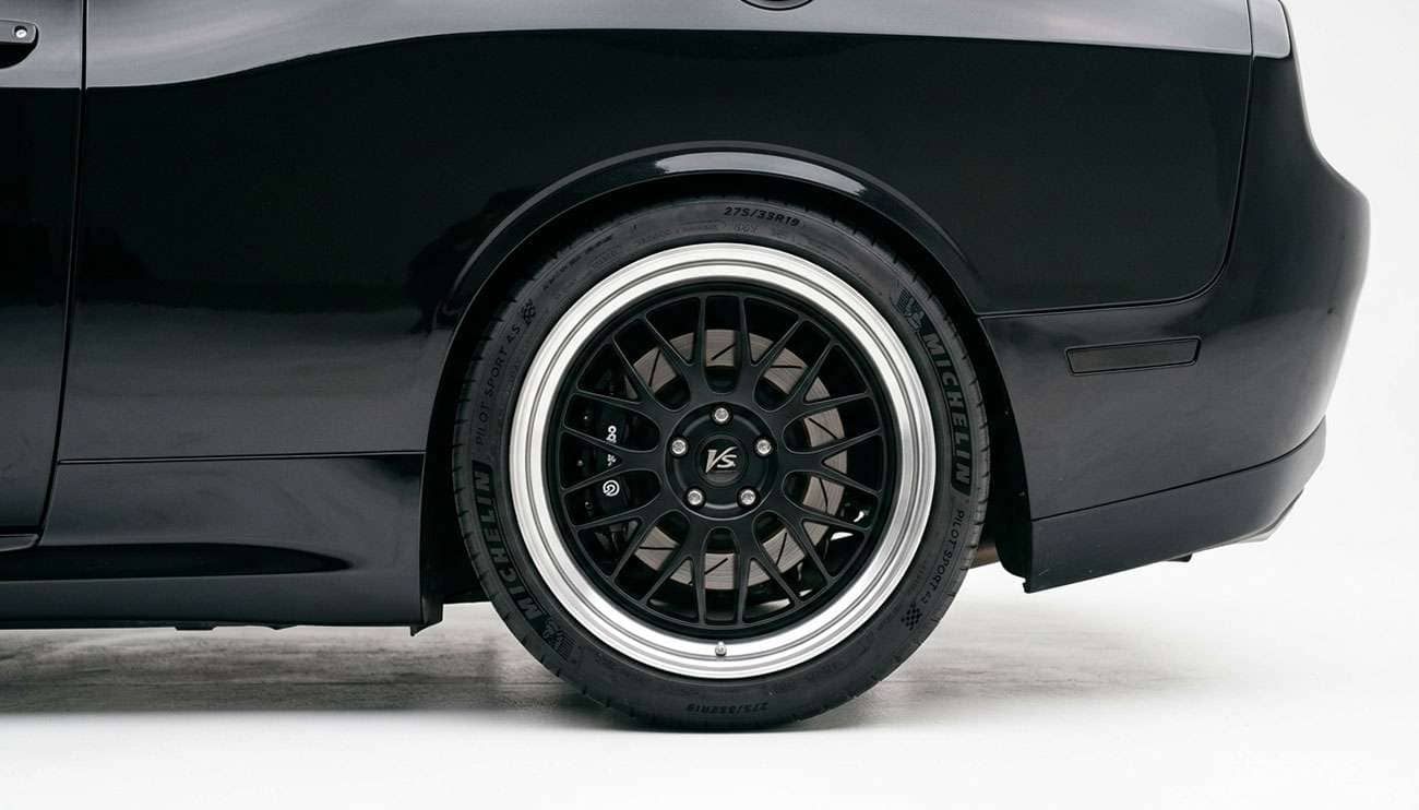 Aftermarket wheel and tire tucked close to a car fender showing tight clearance
