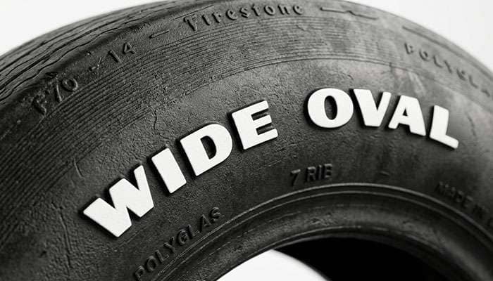 Close-up of Wide Oval raised white lettering on a bias-ply tire sidewall