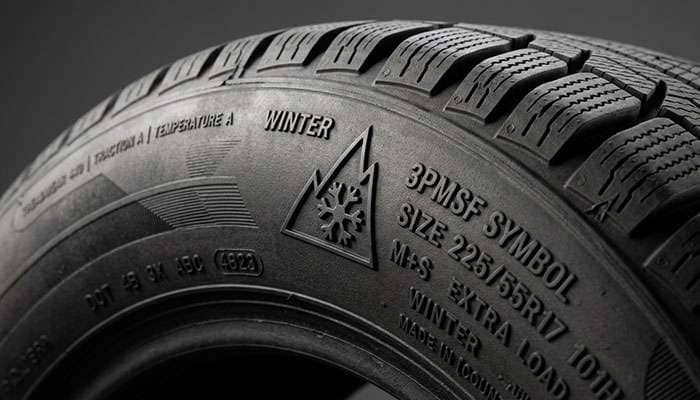Detail of winter tire sidewall showing 3-Peak Mountain Snowflake symbol and aggressive sipe pattern