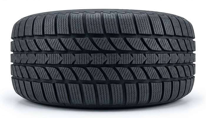 Close-up of winter tire tread pattern showing deep grooves and siping designed for snow and ice traction