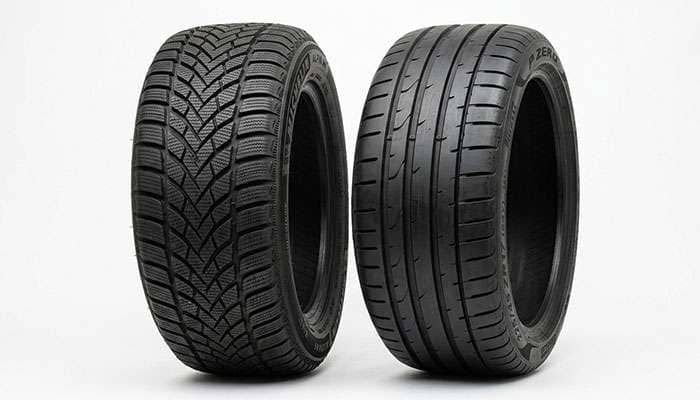 Winter tire with dense siping beside a summer performance tire showing the tread difference between the two types