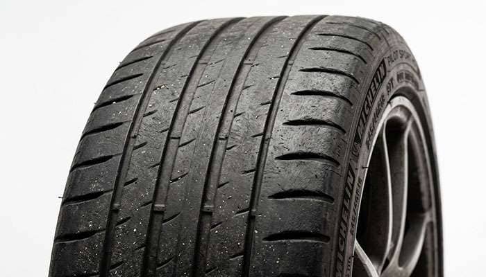 Close-up of a worn front tire tread showing reduced tread depth from steering and braking