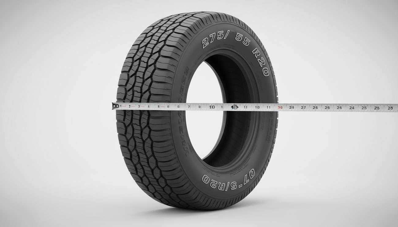 Close-up of a 275/55 R20 tire with a measuring tape across its diameter on a gray background