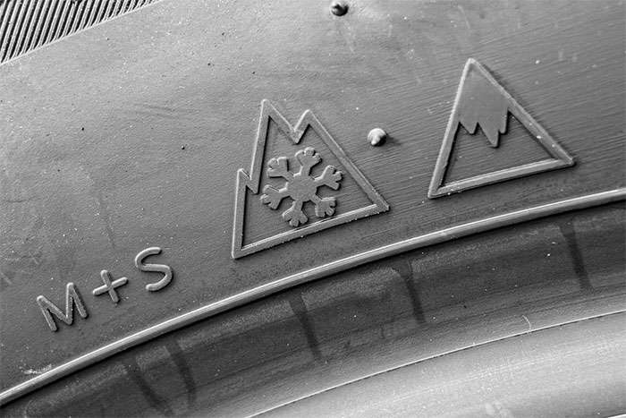 Three-Peak Mountain Snowflake (3PMSF) symbol and Ice Grip marking shown on a tire sidewall for winter certification