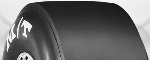 Racing slick tire with minimal tread for maximum grip on dry track surfaces