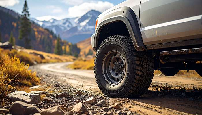 All-terrain tires on pickup truck driving gravel road