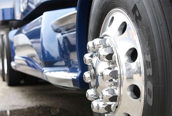 Shiny aluminum wheel on a blue semi-truck demonstrating strength and style
