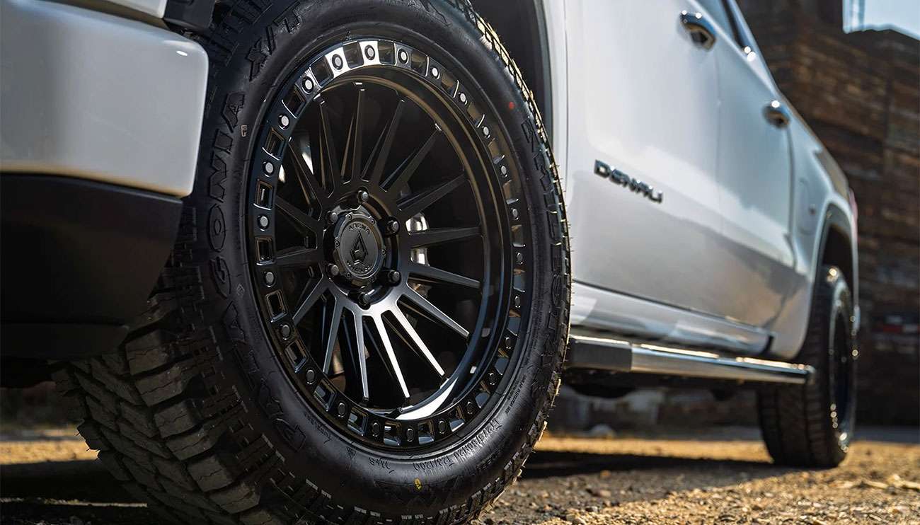 White truck with aggressive off-road Arena wheels on rugged terrain