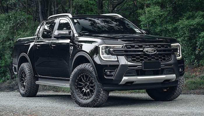 Black Ford 4x4 truck equipped with black Rock CNC wheels parked on a dirt road at dusk
