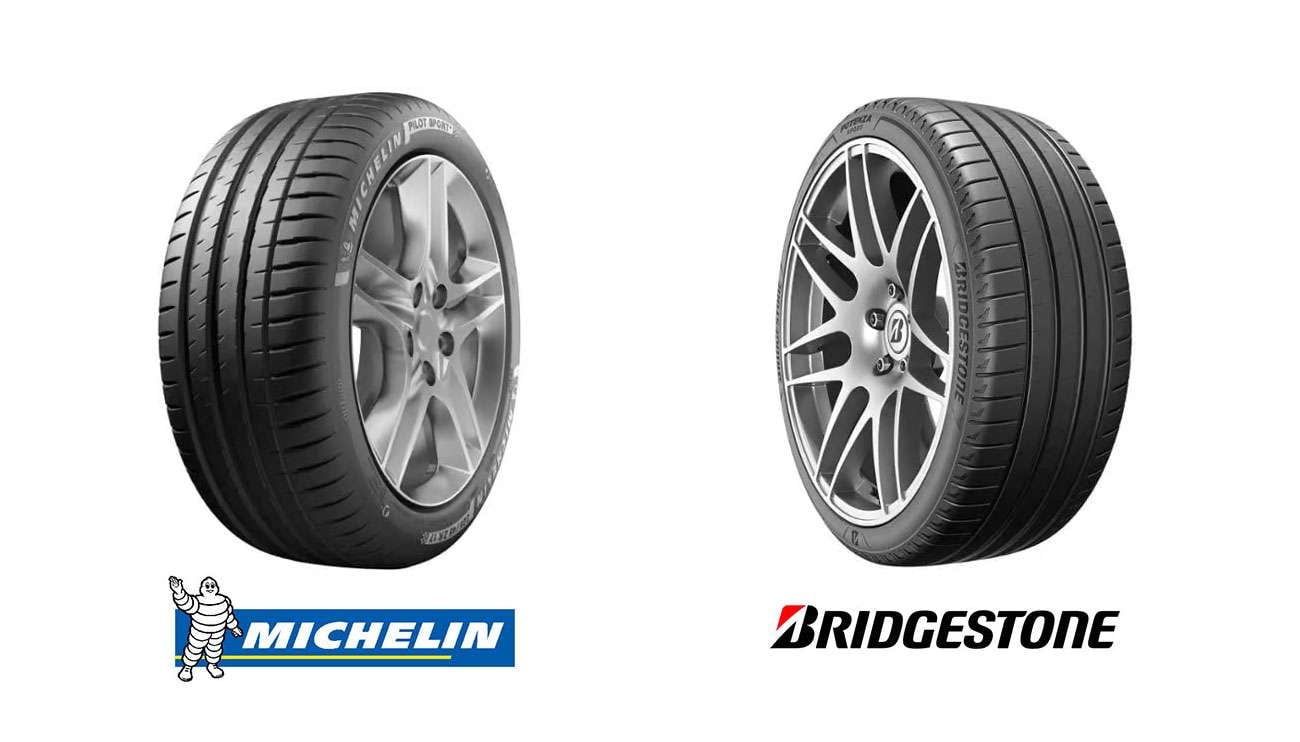 Two premium car tires side by side in a dark room with bright lights, illustrating a comparison between Bridgestone and Michelin tire brands