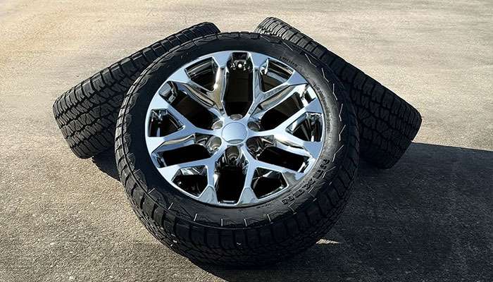 Set of 22 inch chrome snowflake wheels with 275/50R22 all-terrain tires designed for a Chevy Silverado, displayed on concrete