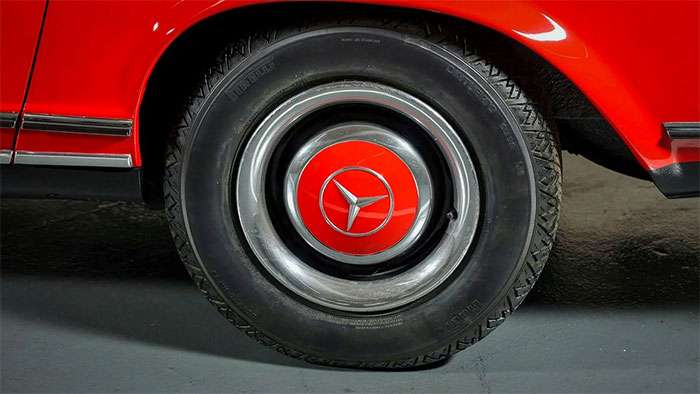Close-up of a classic red Mercedes-Benz car tire with a vintage hubcap and Pirelli branding.