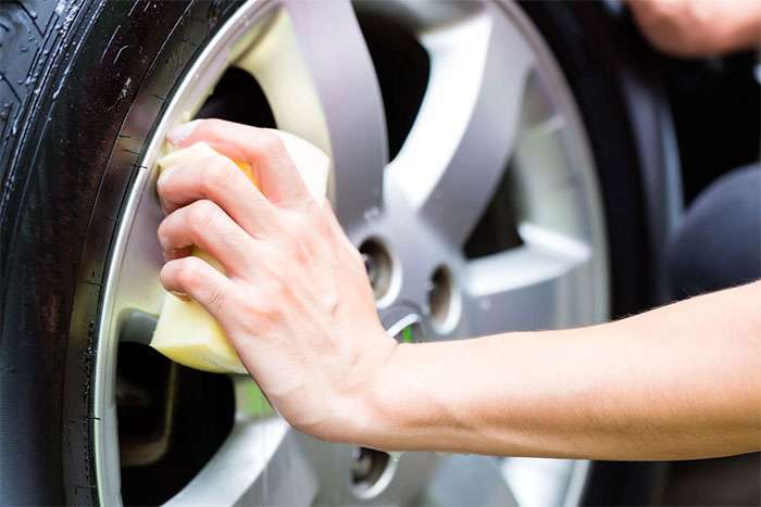 Close-up of a silver alloy rim being cleaned with a sponge