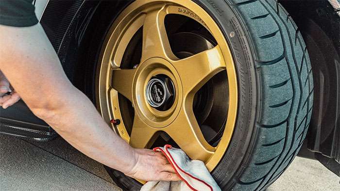 Cleaning a gold Fifteen52 wheel with a cloth during routine maintenance