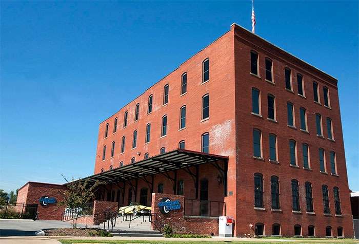 Coker Tire's historic red brick office building with a covered entrance and blue company logos on a sunny day